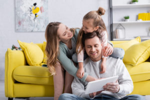 Junges glückliches Paar mit Kind auf einem gelben Sofa
