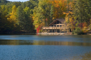 Großes Holzhaus an einem See umgeben von Wald