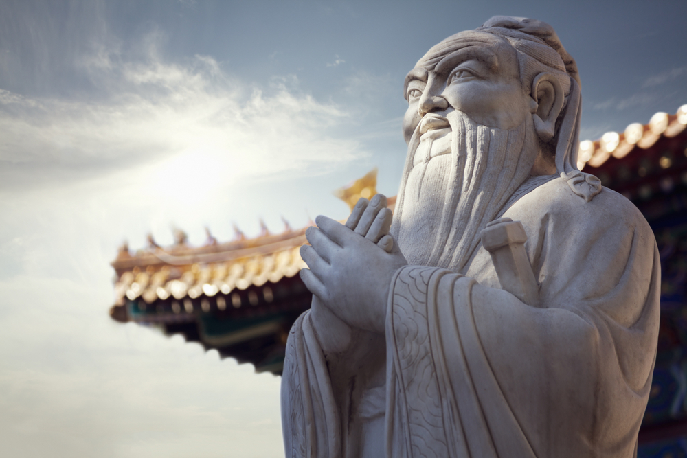 Steinstatue des Konfuzius vor Dach eines Tempels