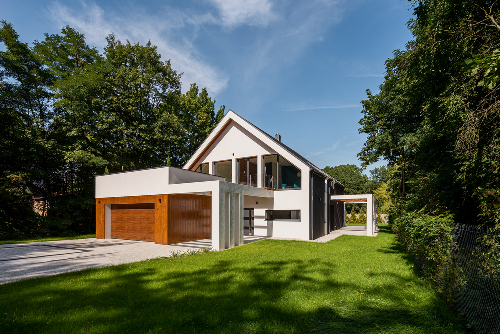 Elegantes weißes Haus mit Wiese und Garage mit Holzfront